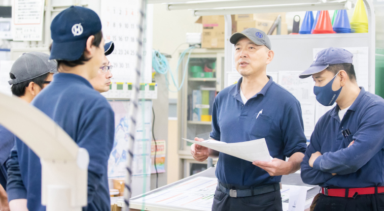 工場で打合せをする人たちの写真